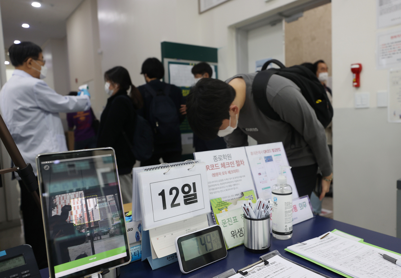 사회적 거리두기 1단계 하향 조정으로 대형 학원 운영이 재개된 가운데 12일 오전 서울 마포구 종로학원 강북본원에서 재원생들이 등원을 하며 발열 체크, 출입명부를 작성 등을 하고 있다. 이날부터 영업이 제한됐던 수도권의 클럽 등 유흥주점, 노래연습장, 대형학원(300인 이상), 뷔페식당 등이 문을 연다. [연합]