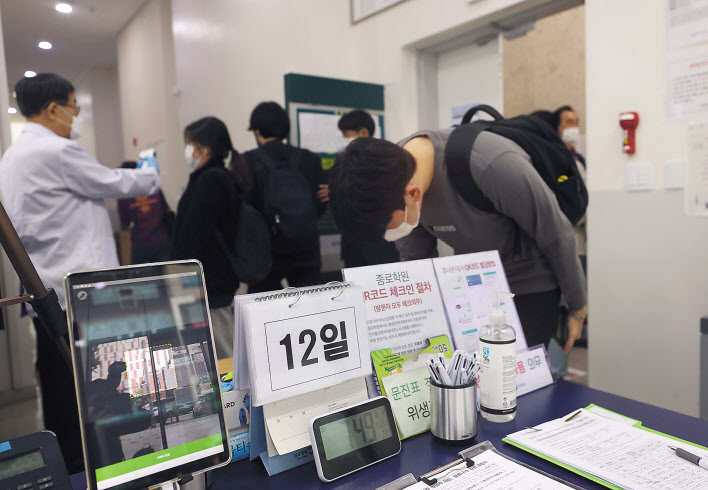 12일 오전 서울 마포구 종로학원 강북본원에서 재원생들이 등원을 하며 발열 체크, 출입명부를 작성 등을 하고 있다. 이날부터 영업이 제한됐던 수도권의 클럽 등 유흥주점, 노래연습장, 대형학원(300인 이상), 뷔페식당 등이 문을 연다. [연합]