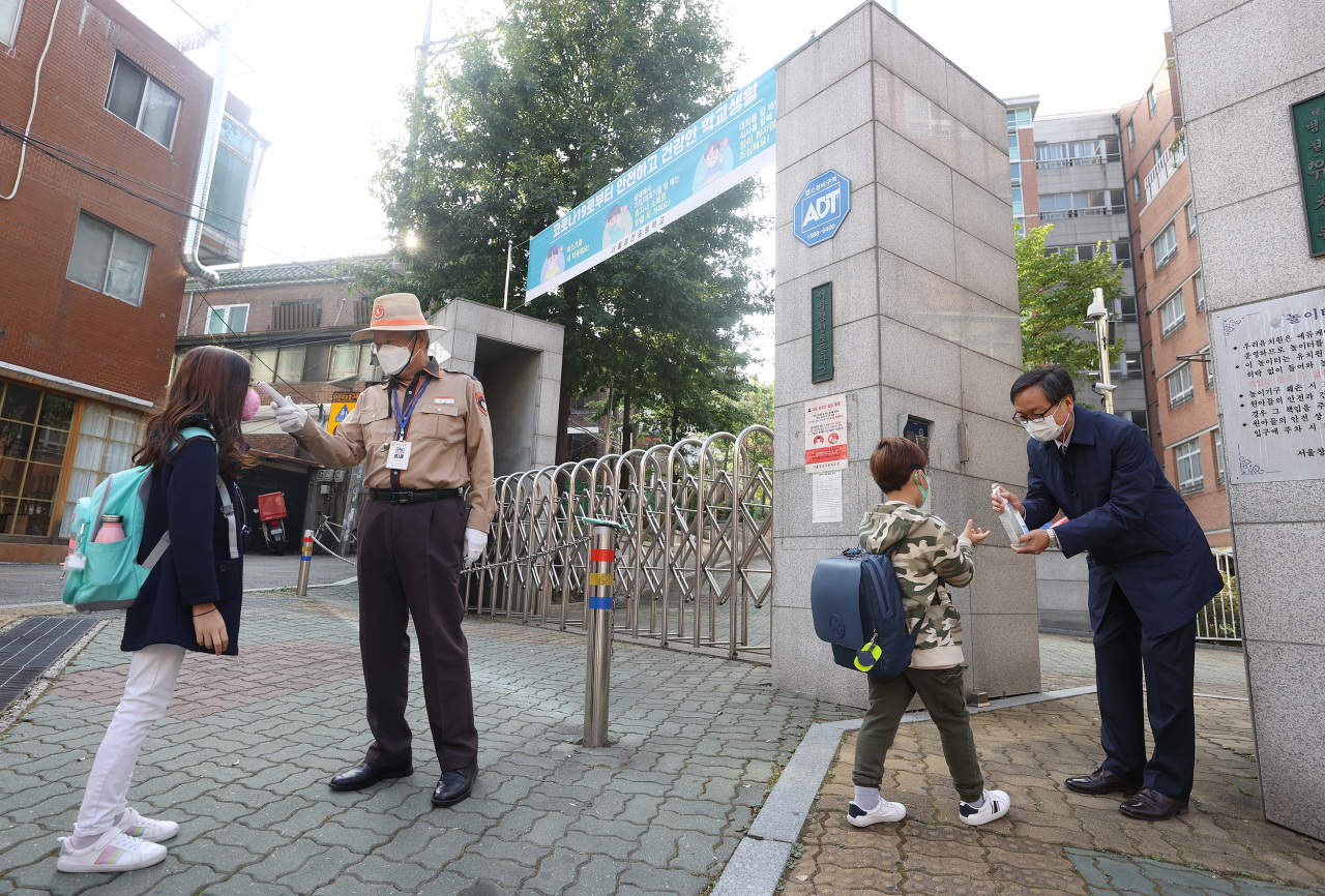 Seoul elementary school children have their temperatures checked and hands sanitized on Monday morning. (Yonhap)