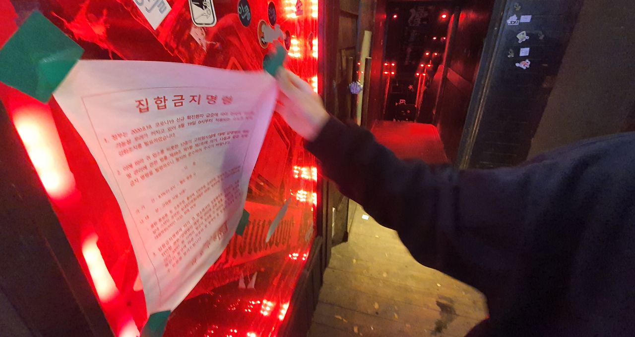 지난 12일 새벽 서울의 한 클럽에서 관계자가 집합금지 안내문을 떼고 있다. 정부는 이날부터 ‘코로나19 방역 대응 사회적 거리두기’를 2단계에서 1단계로 조정했다. [연합]