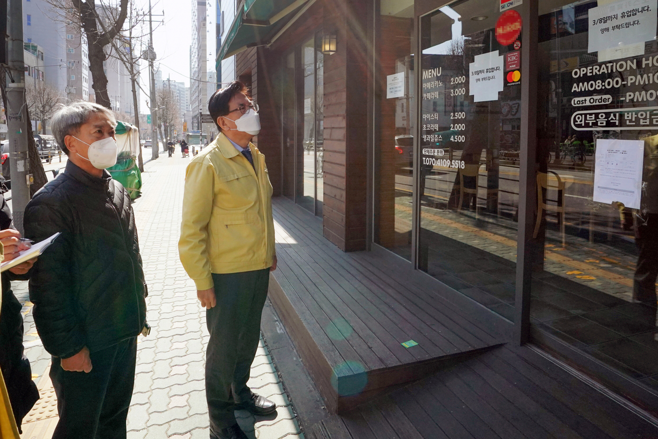 유덕열 동대문구청장(노란색 상의)이 한 커피숍 유리벽에 임시휴업 안내문이 붙은 것을 보고 있다. [동대문구 제공]