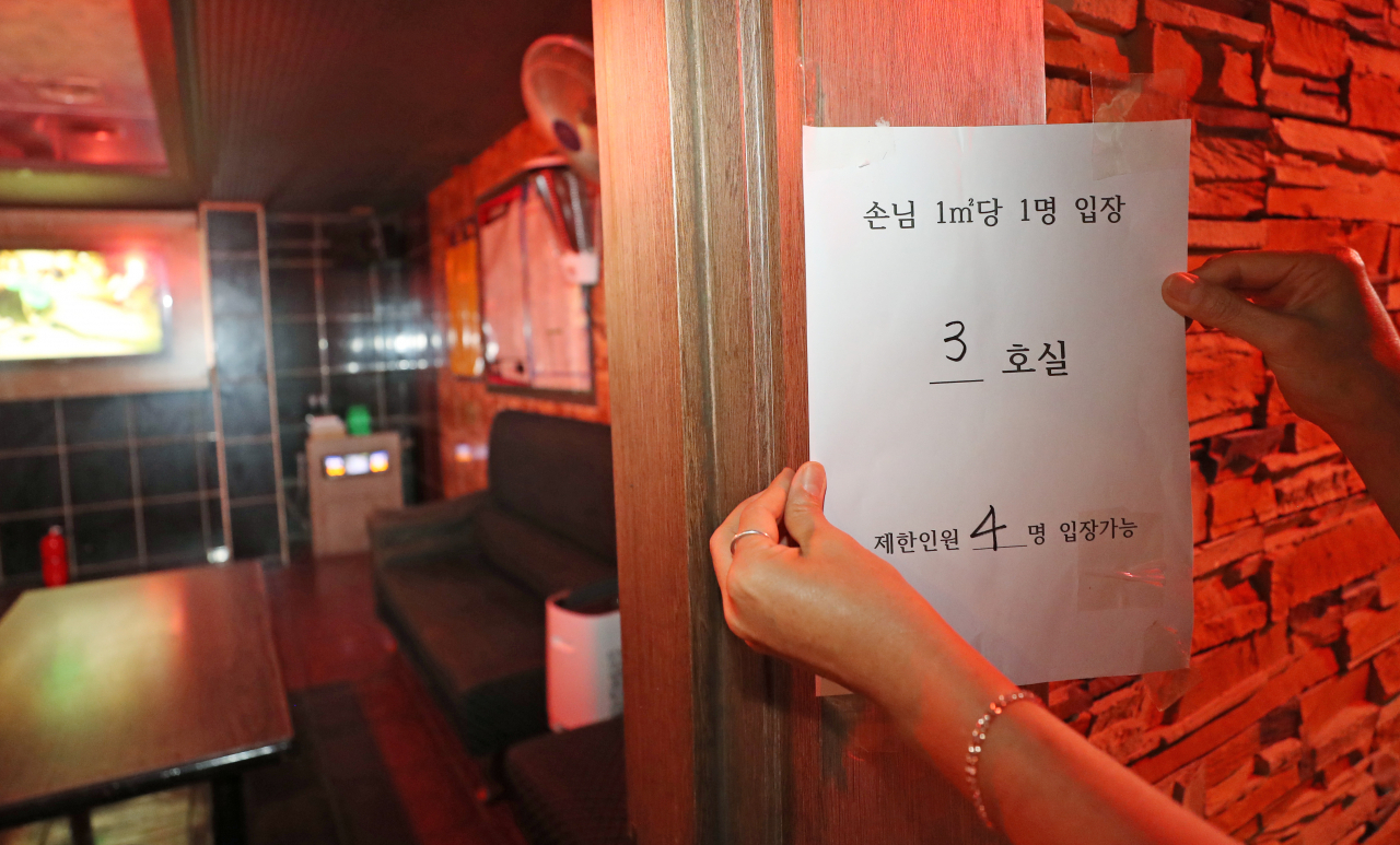 14일 오후 대전시 대덕구 송촌동 한 노래방에서 업주가 입장 인원을 제한하는 내용의 안내문을 붙이고 있다. 신종 코로나바이러스 감염증(코로나19) 확산에 따른 집합금지 조치로 문을 닫았던 대전지역 노래방과 유흥주점 등은 이날 영업을 재개한다. [연합]