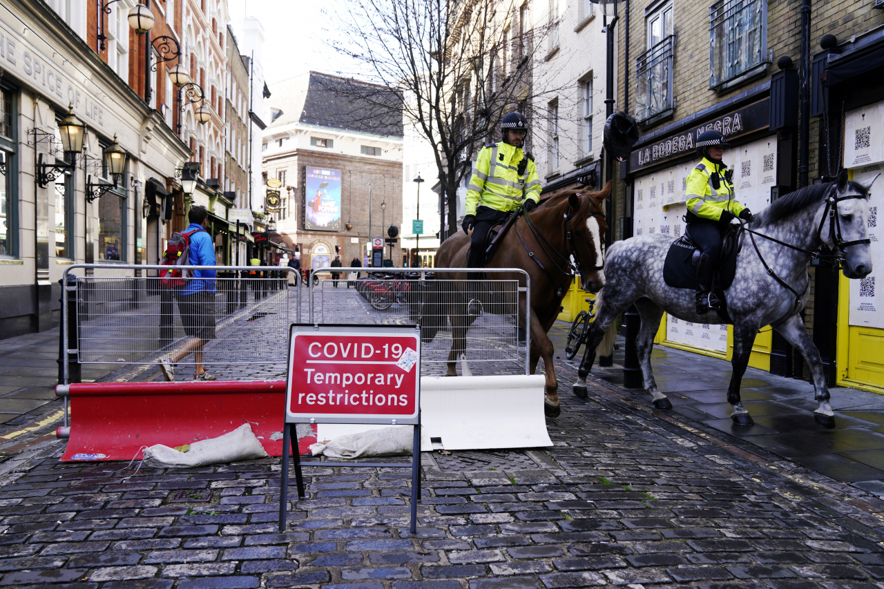 Police horses pass a COVID-19 sign in Central London, Britain. EPA