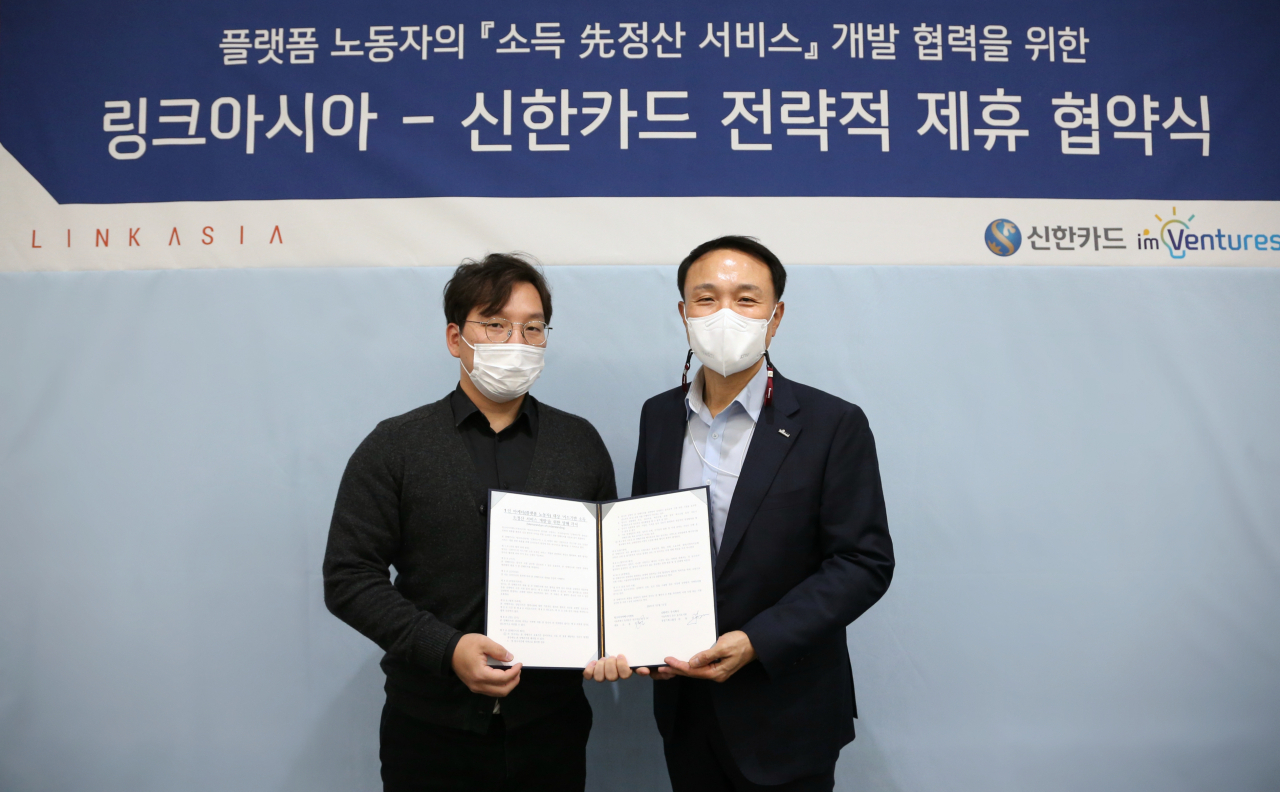신한카드는 링크아시아매니지먼트와 카드기반 소득 선정산 서비스 협업을 위해 서울 을지로에 위치한 신한카드 본사에서 전략적 제휴 협약식을 진행했다고 20일 밝혔다. 조윤호 링크아시아 대표(왼쪽)와 문동권 신한카드 경영기획그룹장(오른쪽)이 제휴 협약서를 들고 기념촬영을 하고 있다.[신한카드 제공]