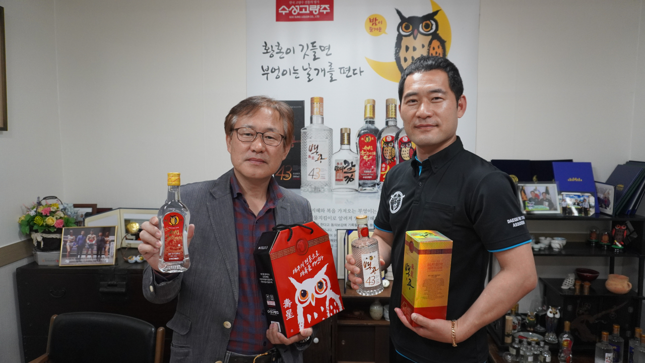 수성고량주 이승로(왼쪽) 대표와 MAX FC 안상욱 기획이사가 대회후원을 기념해 수성고량주 제품들을 들어보이고 있다. [MAX FC 제공]