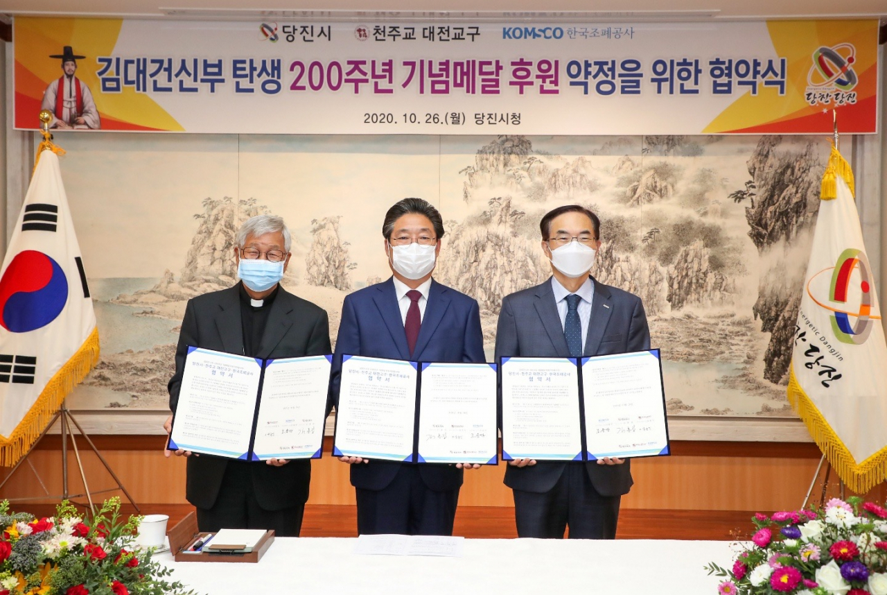 한국조폐공사가 26일 당진시청 및 천주교대전교구와 업무협약을 체결해 내년 김대건 신부 탄생 200주년과 유네스코 세계 기념인물 선정을 기념하는 메달을 출시하고 판매 수익금 일부를 후원하기로 했다. 사진 오른쪽부터 조용만 조폐공사 사장, 김홍장 당진시장, 유흥식 천주교대전교구장. [한국조폐공사 제공]