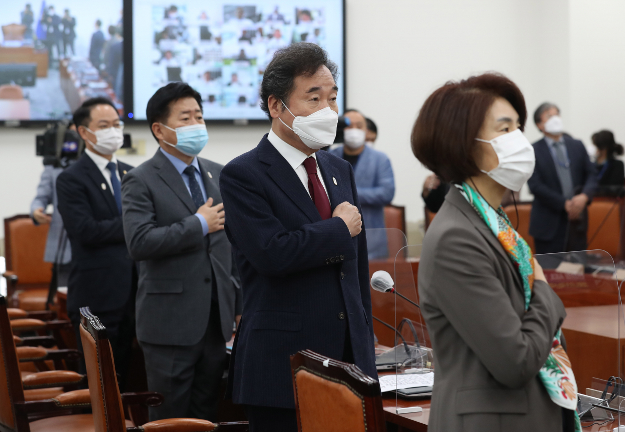 이낙연 더불어민주당 대표와 의원들이 27일 오전 서울 여의도 국회에서 화상 연결로 진행된 온택트 의원총회에서 국기에 경례를 하고 있다. [연합]