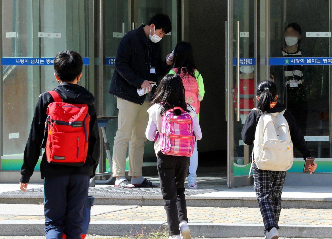 전국 유·초·중·고교 등교인원 제한이 완화된 19일 부산시 부산진구 부암초등학교에서 학생들이 교실로 들어가기 전 발열체크를 받고 있다. [연합]