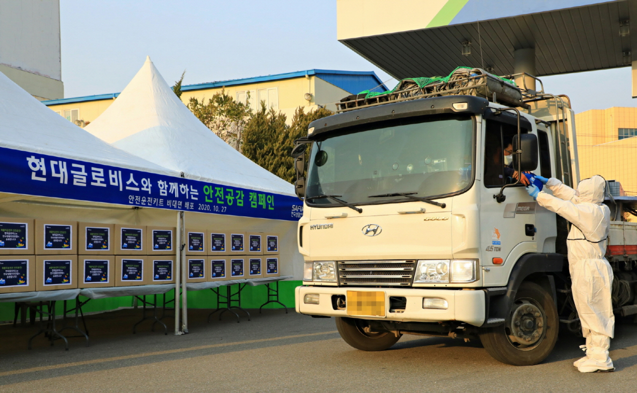 현대글로비스 관계자가 지난 27일 청주화물터미널을 이용하는 화물차 운전자에게 안전운전용품 세트를 ‘드라이브 스루’ 방식으로 전달하고 있다. [현대글로비스 제공]