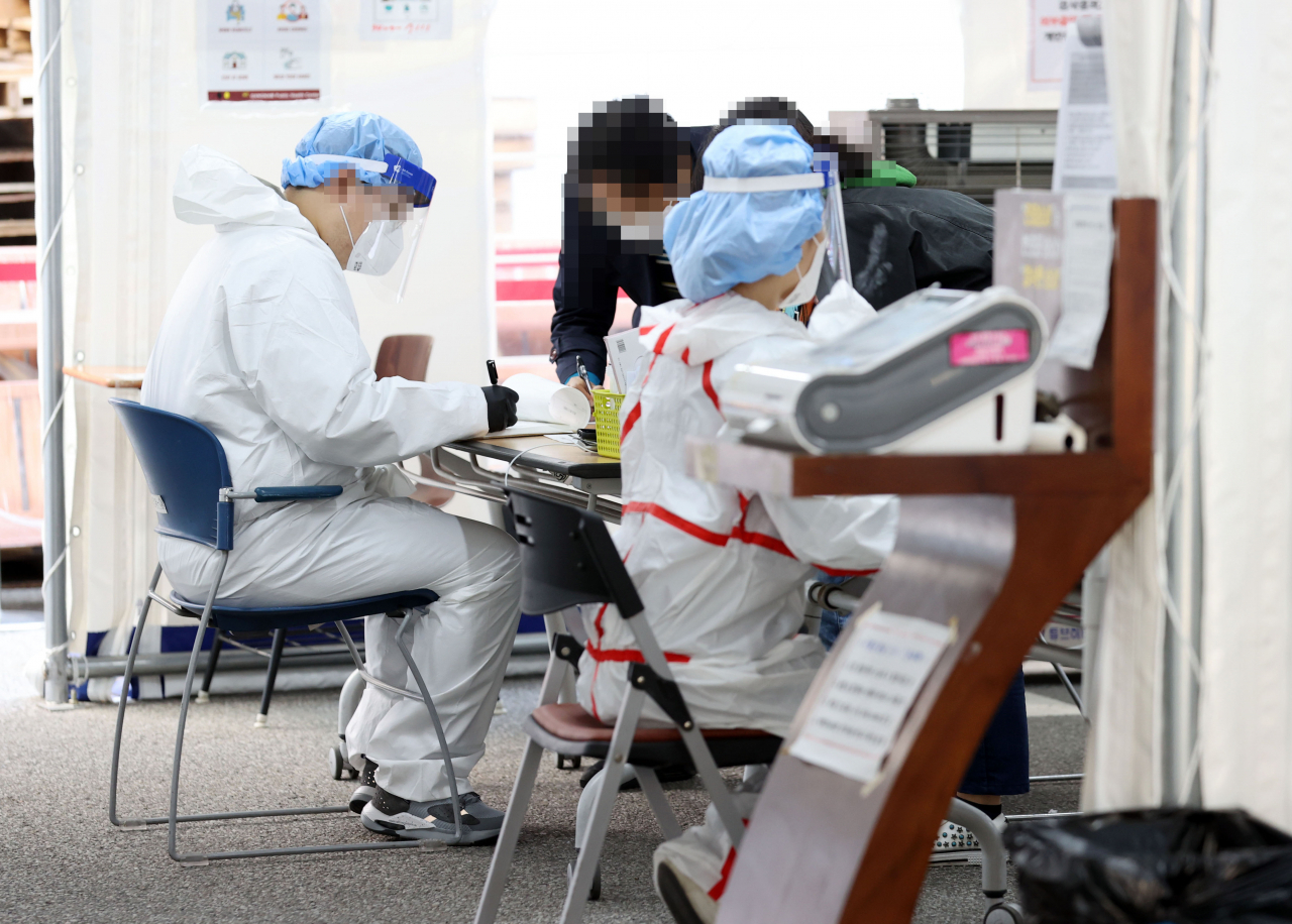 29일 오전 서울 강남구보건소 신종 코로나바이러스 감염증(코로나19) 선별진료소에서 의료진이 시민들 문진표 작성을 돕고 있다. [연합]