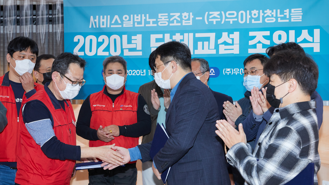 22일 서울 송파구에서 진행된 우아한청년들과 민노총 서비스일반노동조합의 단체교섭 조인식에서 우아한청년들 김병우 대표(오른쪽)와 민주노총 서비스일반노조 이선규 위원장이 국내 첫 플랫폼 기업과 종사자 간 단체협약에 서명한 뒤 악수를 하고 있다. [우아한형제들 제공]