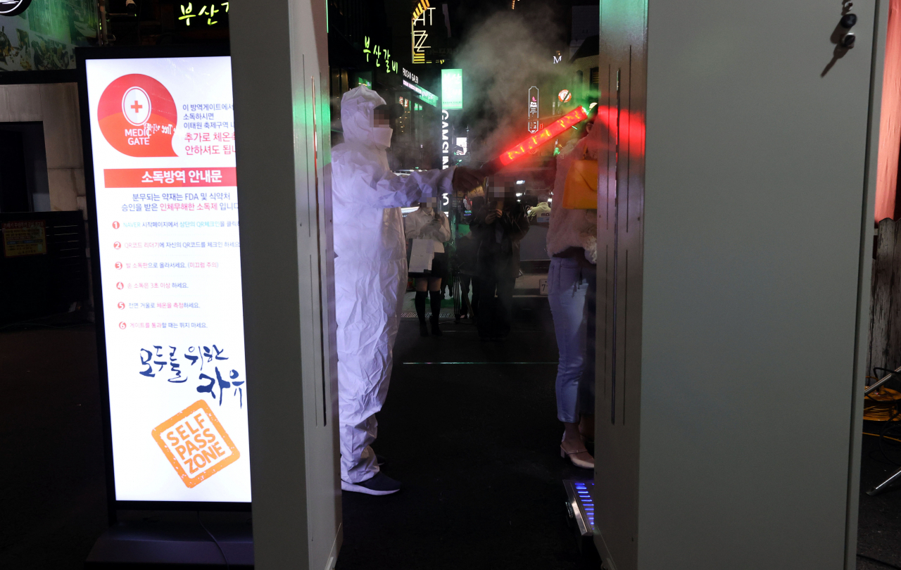 핼러윈 데이를 하루 앞둔 30일 오후 서울 용산구 이태원 거리 입구에 설치된 신종 코로나바이러스 감염증(코로나19) 방역 게이트를 시민들이 통과하고 있다. [연합]