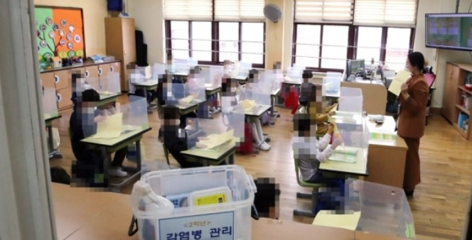 초등학생들이 가림막이 설치된 교실에서 마스크를 쓴 채 수업에 임하고 있다.[연합]