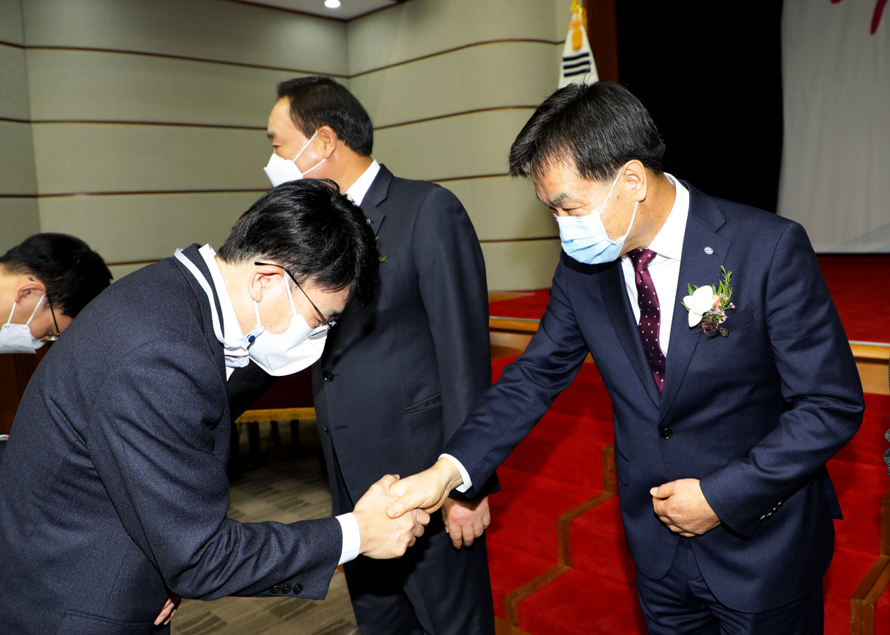 김진균 신임 Sh수협은행장이 취임식에서 국민의례를 하는 모습(左). 취임식 후 참석자들과 악수로 인사를 나누고 있다 [Sh수협은행 제공]