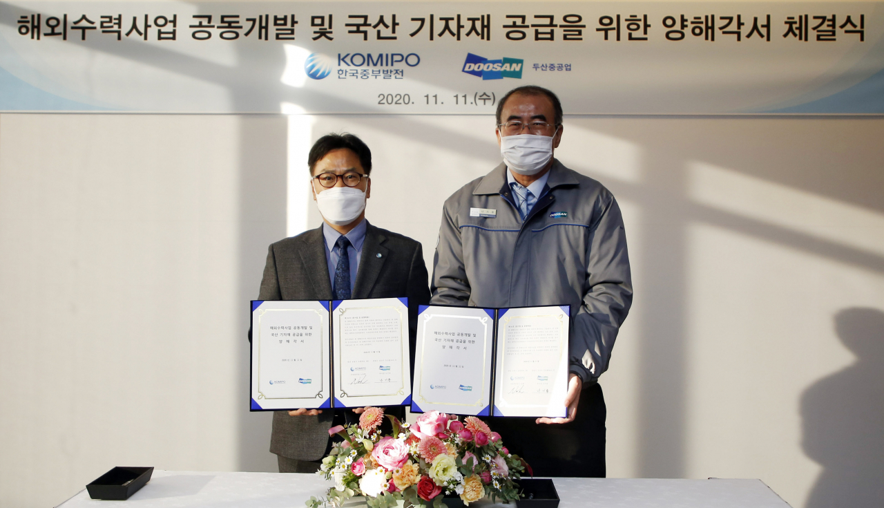 지난 11일 두산중공업 창원 본사에서 열린 해외수력사업 공동개발 및 국산 기자재 공급을 위한 양해각서 체결식에서 노웅환 한국중부발전 사업본부장 (왼쪽)과 나기용 두산중공업 부사장이 협약 체결 후 기념촬영을 하고 있다.[두산중공업 제공]