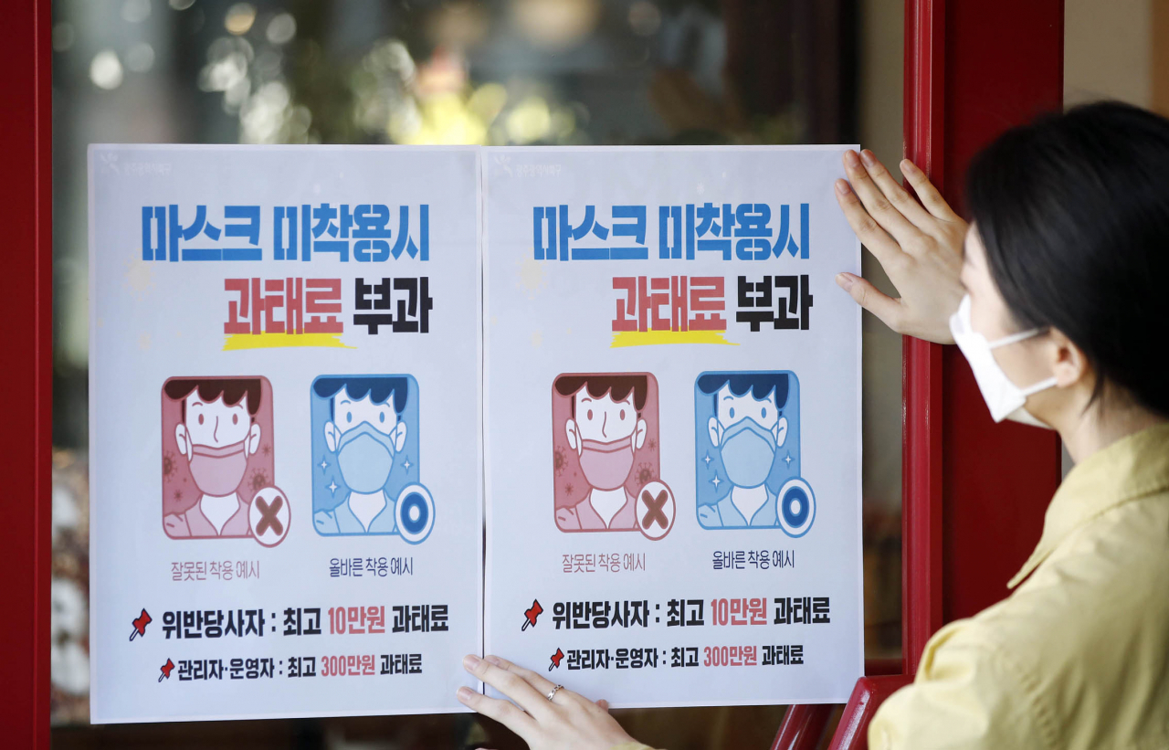 12일 오전 광주 북구의 한 커피숍에서 광주 북구보건소 감염병관리팀 직원들이 마스크 착용 의무화 시행으로 오는 13일부터 미착용 시 과태료를 부과한다는 안내문을 붙이고 있다. 연합뉴스