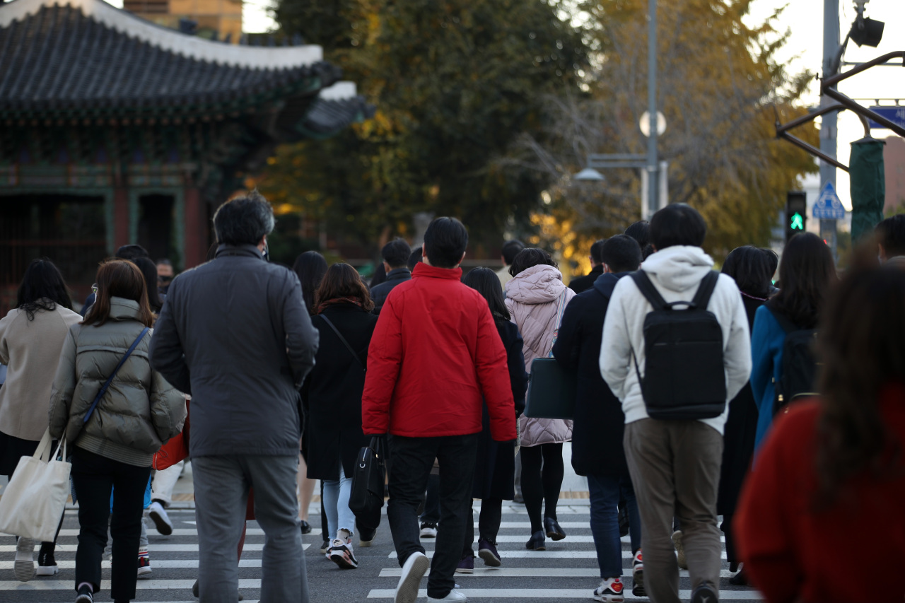 People walk across a pedestrian crossing in Gwanghwamun, central Seoul, on Tuesday when temperatures plunged below 5 degrees Celsius. (Yonhap)