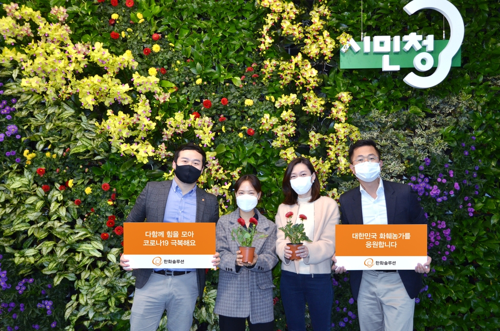 한화솔루션은 김동관 전략 부문 사장이 '플라워 버킷 챌린지'에 동참하며 서울시청 시민청 내 친환경 플라워 아트월 조성을 지원했다고 15일 밝혔다. 사진은 플라워 아트월 앞에서 사진 촬영하는 한화솔루션 직원들. [한화솔루션 제공]