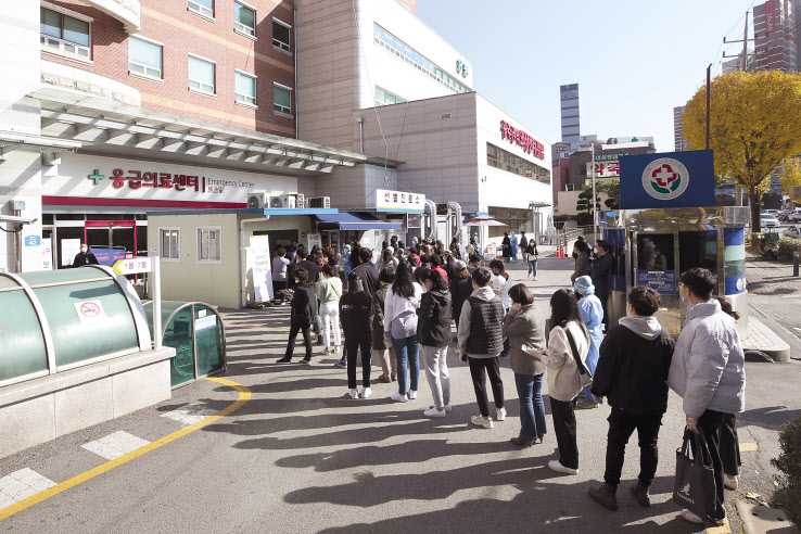15일 오후 광주 동구 전남대병원 선별진료소에서 직원과 환자·보호자 등이 신종 코로나바이러스 감염증(코로나19) 검사를 받기 위해 줄을 서 있다. 전남대병원은 최근 소속 전공의를 비롯한 의료진과 환자·보호자가 잇따라 확진 판정을 받자 5000여명을 대상으로 전수 검사를 하고 있다. [연합]