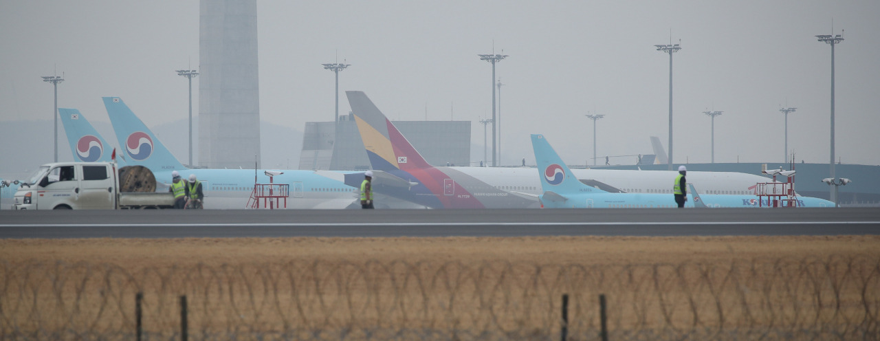 대한항공의 아시아나항공 인수 발표가 하루 지난 17일 오후 인천국제공항 제4활주로 공사현장 뒤로 대한항공과 아시아나항공 여객기들이 세워져 있다. [연합뉴스]