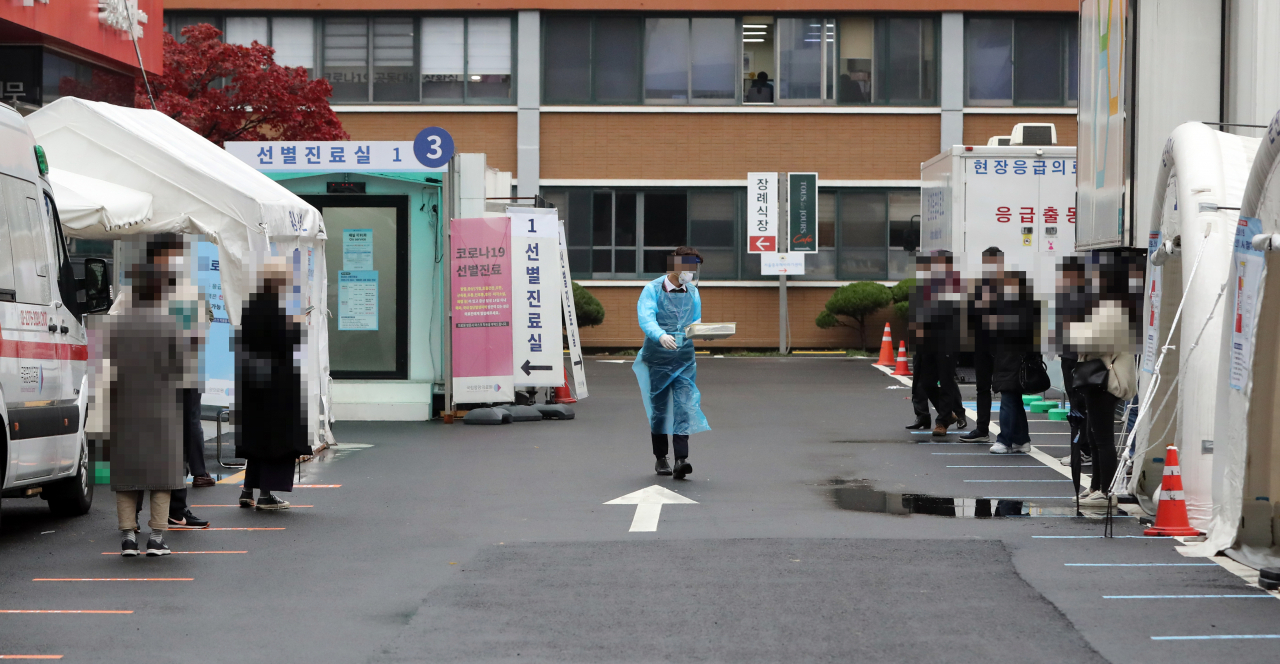 18일 서울 국립중앙의료원 코로나19 선별진료소에 검사를 받으려는 시민들이 대기하며 관계자의 안내를 받고 있다. [연합]