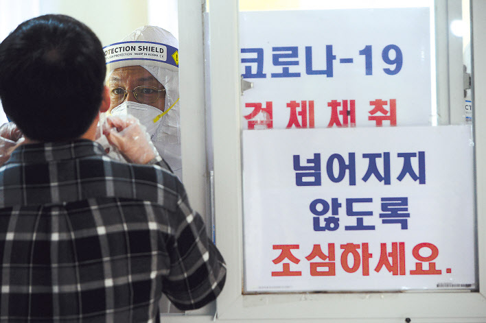 코로나19 확진자의 증가로 사회적 거리두기 단계를 1.5단계로 격상하기로 한 지역이 늘고 있는 가운데 18일 오전 서울 성동구보건소 코로나19 선별진료소를 찾은 시민이 검체채취를 하고 있다. 박해묵 기자