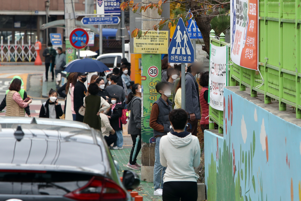 18일 오후 광주 서구 한 초등학교 정문에서 학부모가 하교하는 아이들을 기다리고 있다. 광주에서는 전남대학교병원을 중심으로 신종 코로나바이러스 감염증(코로나19)이 확산하자 확진자의 가족이 다니는 각급 학교 7곳에서 전수 검사와 전교생 대기가 이어졌다. 연합뉴스