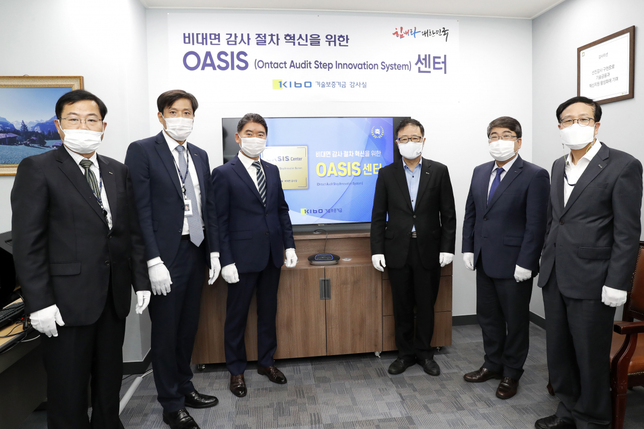 기술보증기금이 19일 부산의 본사 3층에서 정윤모 이사장(오른쪽 세번째) 등이 참석한 가운데 비대면 감사 시스템인 오아시스 센터 구축을 알리는 현판식을 진행했다.[기술보증기금 제공]