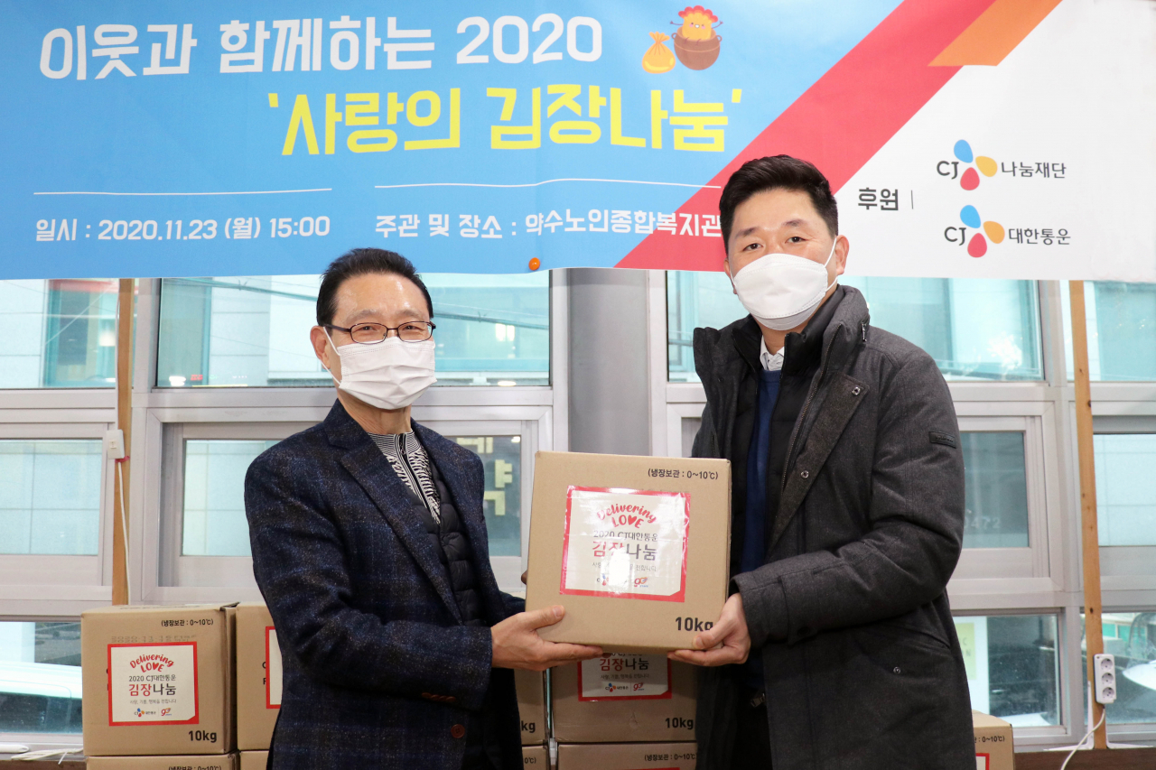 박진규 CJ대한통운 부장(오른쪽)과 민진암 구립약수노인종합복지관장이 ‘2020 사랑의 김장김치 나누기’ 전달식에서 기념사진을 촬영하고 있다. [CJ대한통운 제공]