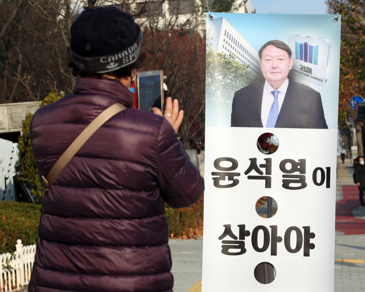 26일 오전 서울 서초구 대검찰청 앞에서 한 시민이 윤석열 검찰총장의 모습이 나온 배너를 휴대전화 카메라로 찍고 있다. 윤석열 검찰총장은 직무배제 하루만인 지난 25일 밤 법원에 온라인으로 추미애 법무부 장관의 직무정지 조치에 대한 집행정지를 신청했다. [연합]