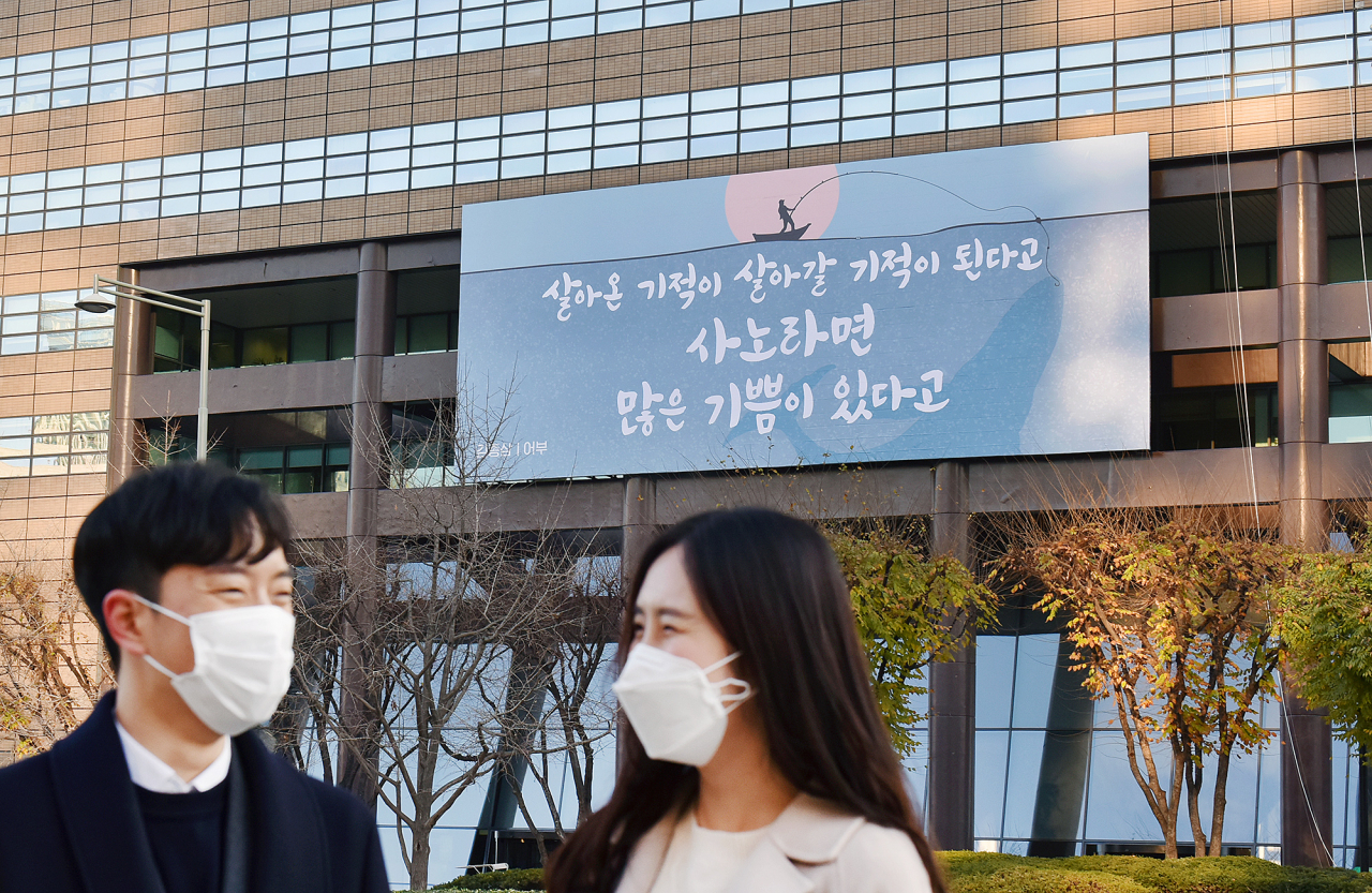 30일 마스크를 쓴 시민들이 교보생명 광화문글판 '겨울편'이 내걸린 광화문 교보생명빌딩 주변을 걷고 있다.
