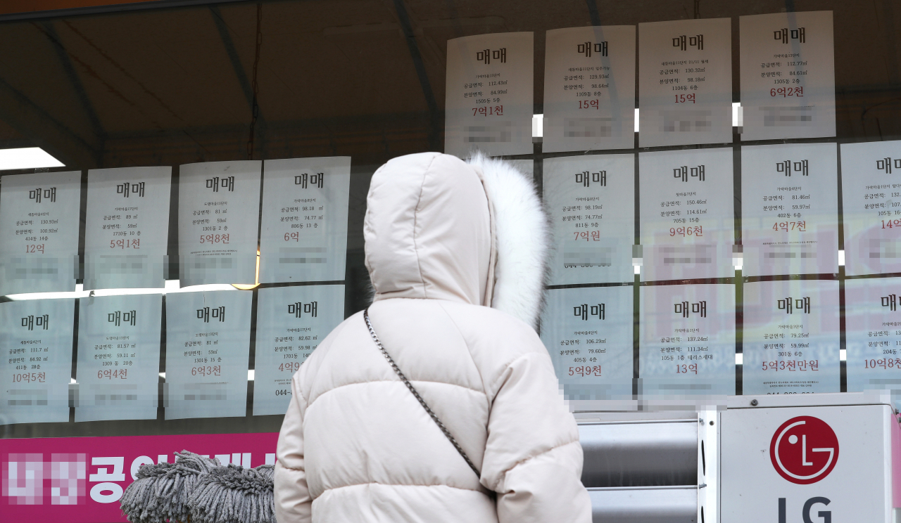 세종시의 한 공인중개사 유리창에 붙은 아파트 매매가격표를 한 시민이 바라보고 있다. [연합뉴스]