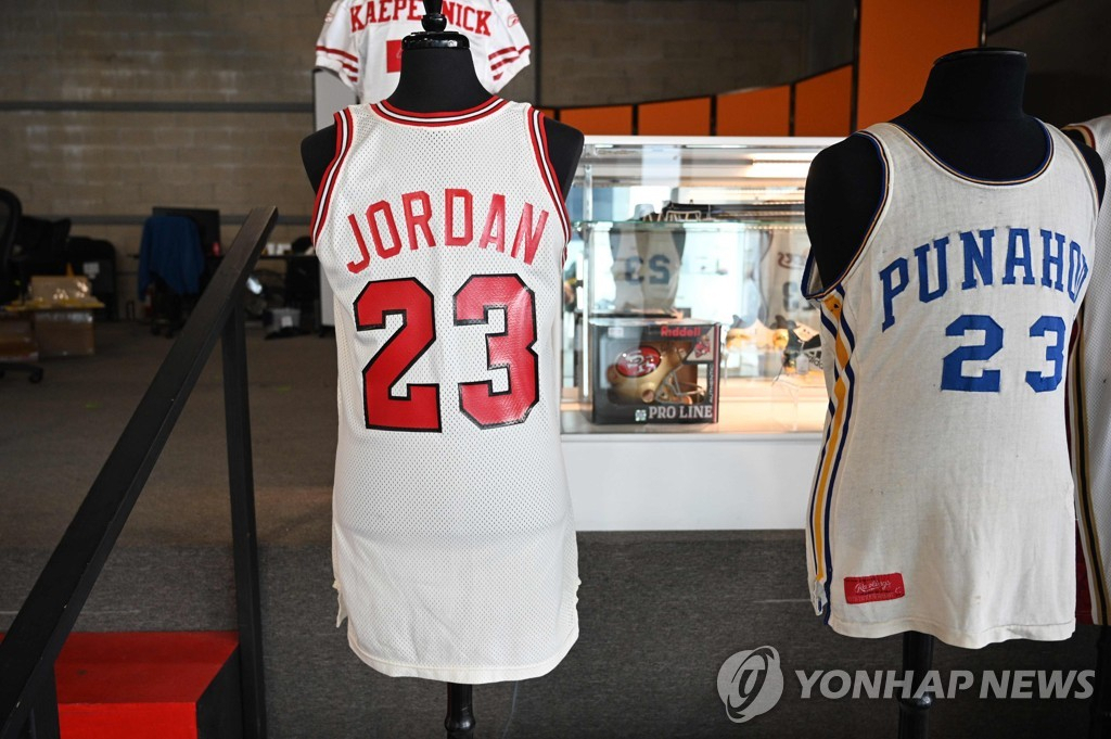 마이클 조던이 1984년 NBA 시카고 불스에 지명된 후 기자회견에서 들어 올린 유니폼 상의. 우측에는 버락 오바마 전 대통령의 고교 시절 농구 유니폼 상의.[AFP=연합]