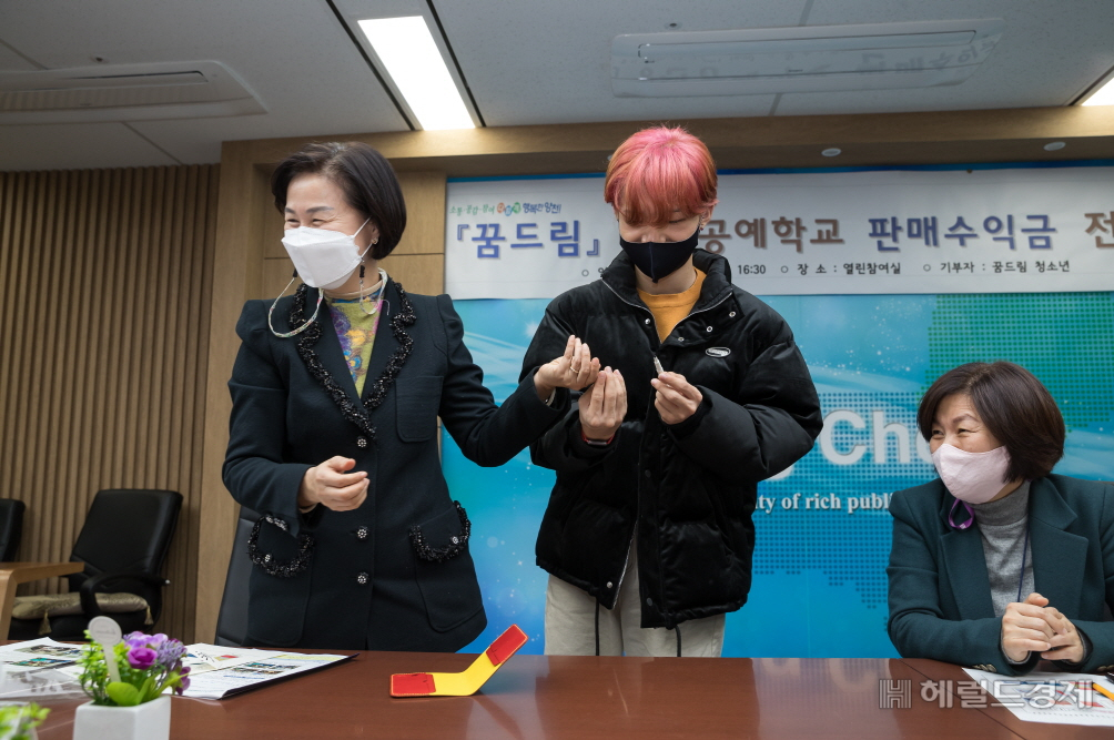 지난 1일 성금 기탁식에서 김수영 구청장(왼쪽)과 학교 밖 청소년이 가죽공예품을 보며 웃고 있다.