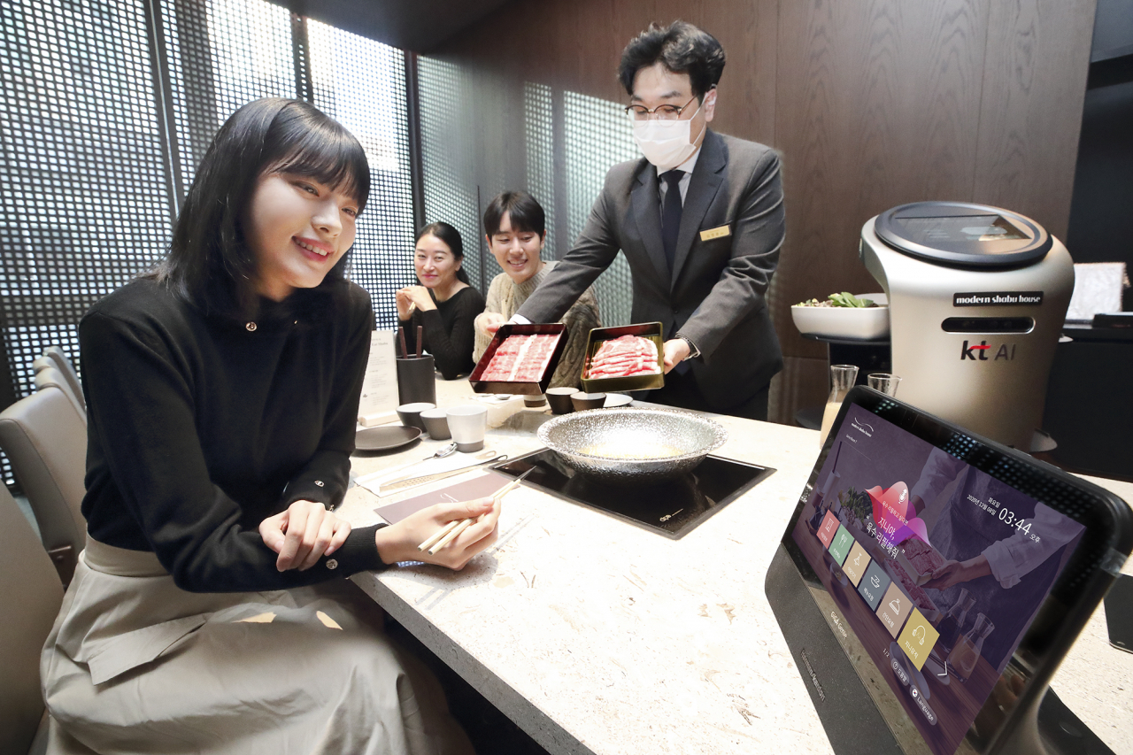 KT는 외식업체 썬앳푸드와 손잡고 AI 기반 외식업계 디지털 혁신(DX) 시범 서비스를 선보인다고 9일 밝혔다. 사진은 모델이 ‘모던 샤브 하우스 광화문D타워점’에서 서비스를 체험하고 있는 모습. [KT 제공]