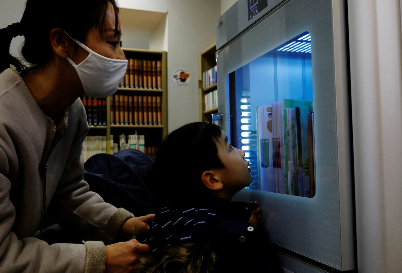 일본 도쿄의 한 도서관에서 한 소년이 신종 코로나바이러스 감염증(코로나19) 확산 방지를 위한 자외선 살균기를 살펴보고 있다. [로이터]