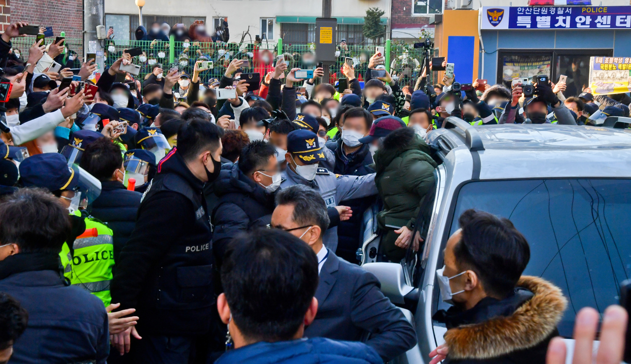 Cho Doo-soon is surrounded by protesters Saturday as he exits police vehicle that escorted to his residence in Ansan, Gyeonggi Province. (Yonhap)