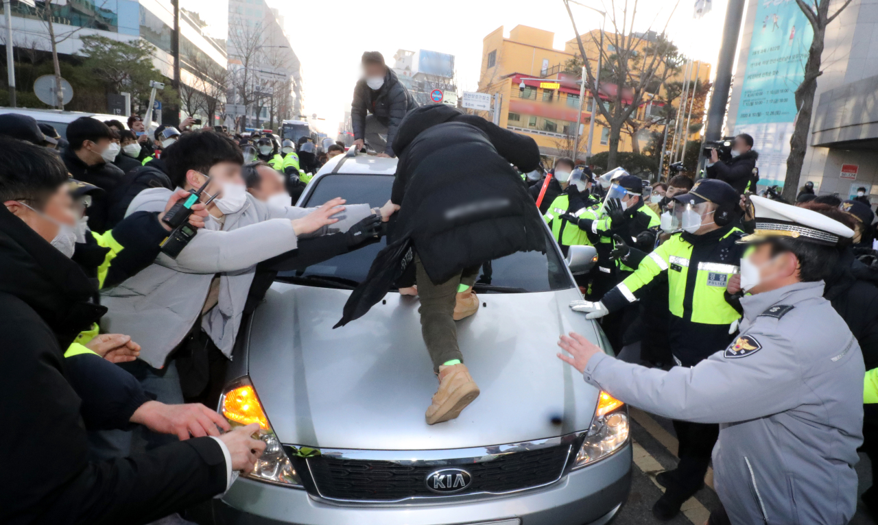 Demonstrators near a compliance support center in Ansan, Gyeonggi Province, block the way and damage a police vehicle escorting infamous child rapist Cho Doo-soon to his home in the city on Saturday. (Yonhap)