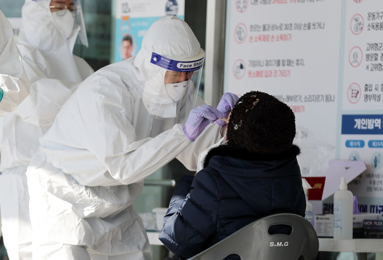 A health worker at a North Jeolla Province testing center takes nasal swab sample from a potential patient on Tuesday. (Yonhap)