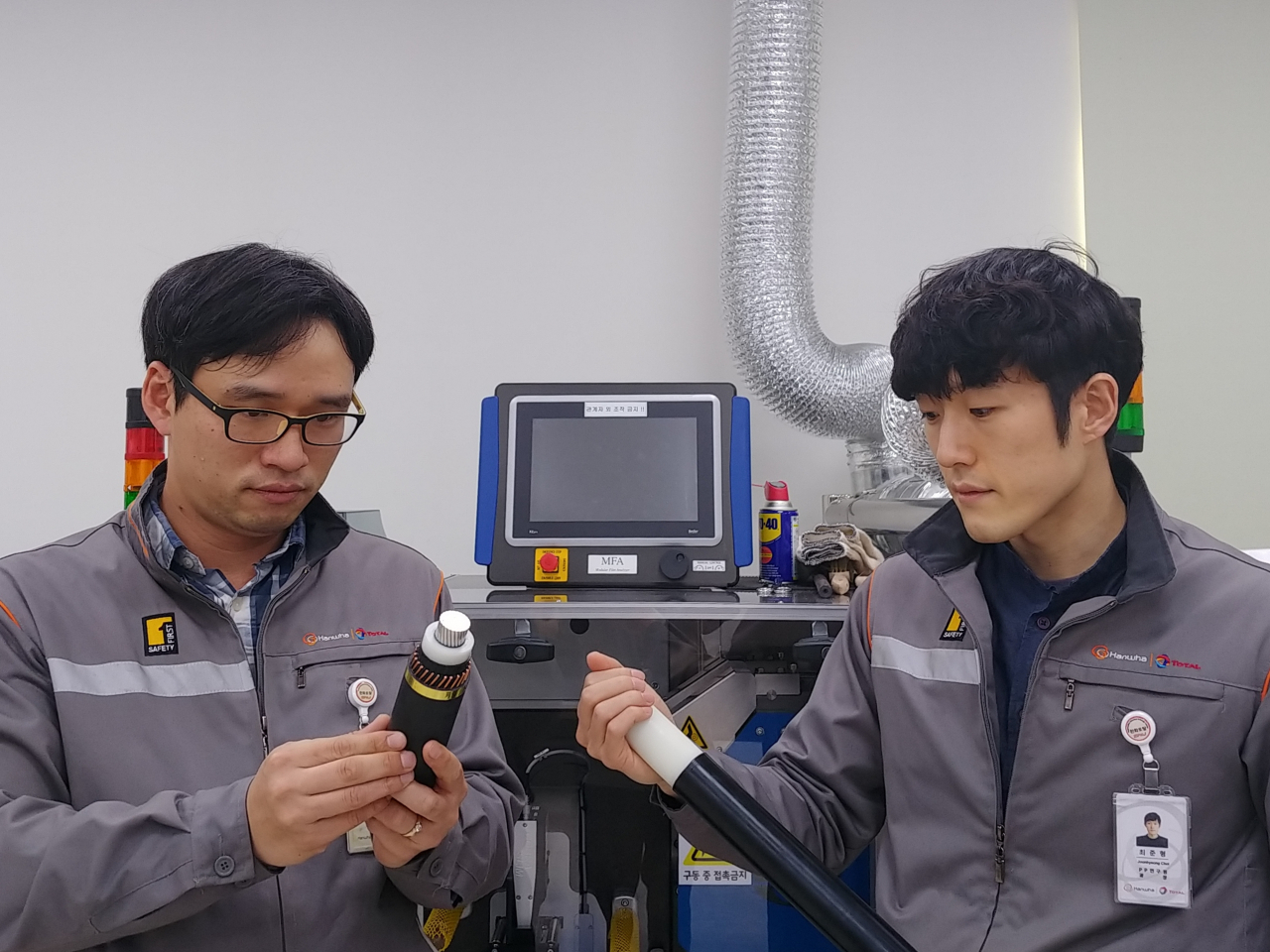 한화토탈 연구원들이 국가기술표준원으로부터 신기술 인증을 받은 ‘재활용이 가능한 전력 케이블용 폴리프로필렌’(전력 케이블 흰 색 중간층)을 살펴보고 있다. [한화토탈 제공]