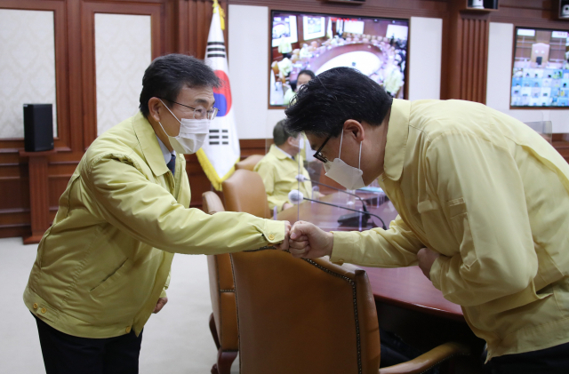 전해철 행정안전부 장관(왼쪽)이 24일 오전 정부서울청사에서 열린 신종 코로나바이러스 감염증(코로나19) 대응 중앙재난안전대책본부(중대본) 회의에 참석해 권덕철 신임 보건복지부 장관과 주먹인사를 하고 있다. [연합]