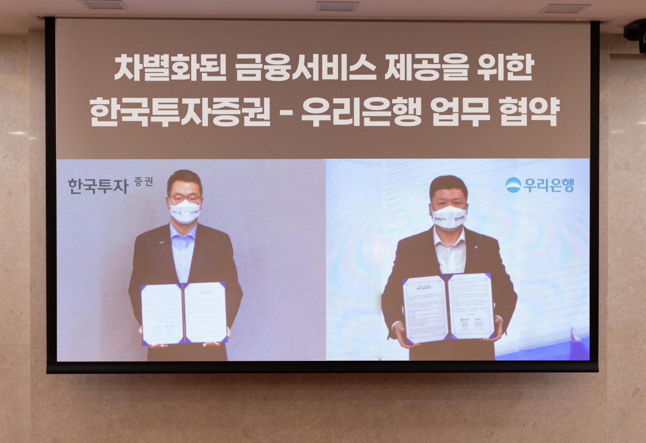 지난 23일 정일문 한국투자증권 사장(왼쪽)과 권광석 우리은행장이 각 사에 마련된 화상회의실에서 비대면 업무협약식을 진행하고 기념사진을 촬영하고 있다.[한국투자증권 제공]