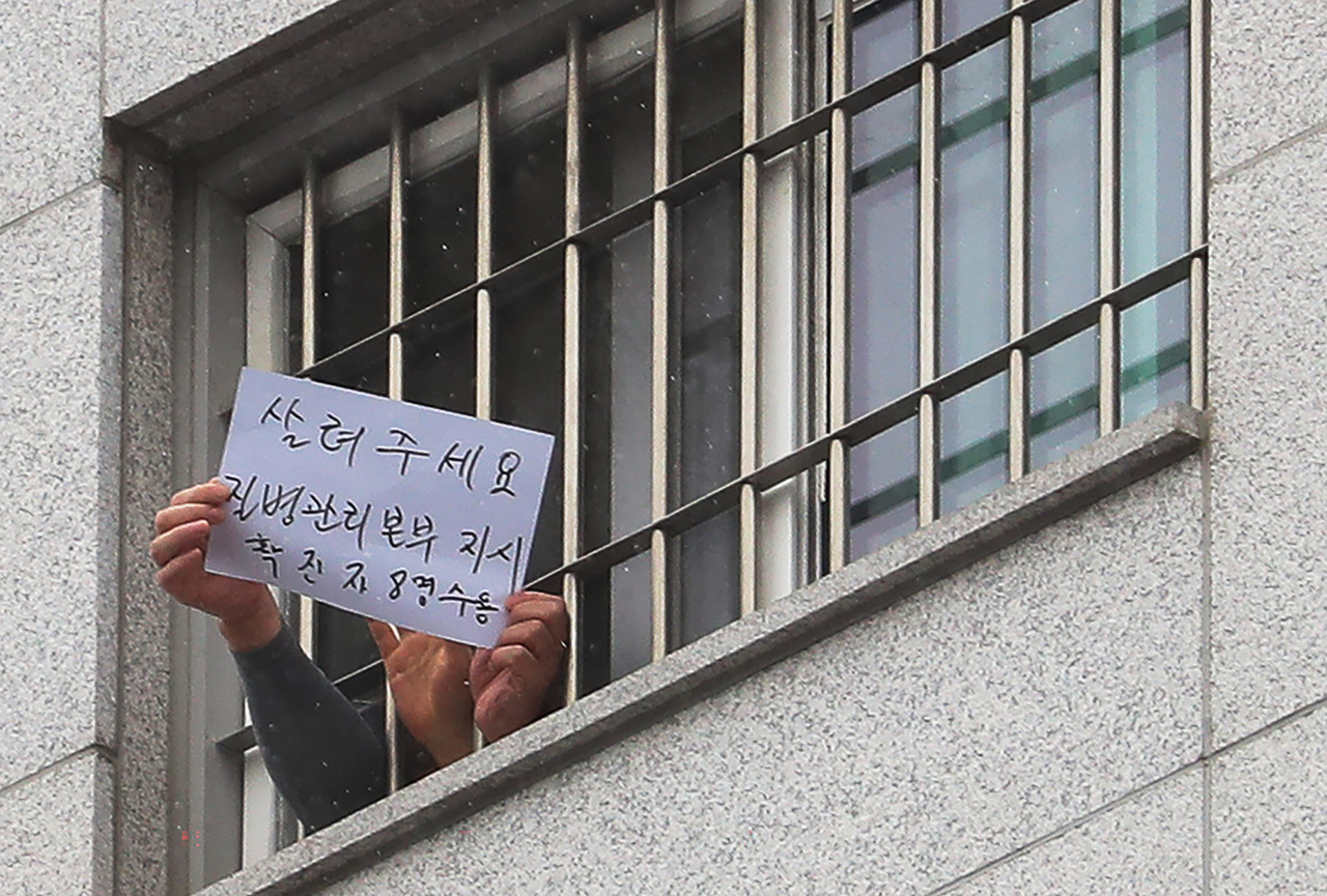 지난달 29일 오후 서울 송파구 동부구치소에서 수용자들이 확진자 과밀수용 등 불만 사항을 직접 적어 취재진을 향해 들어 보이고 있다. [연합]