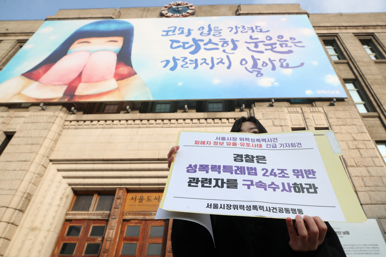 서울시장위력성폭력사건공동행동이 지난 28일 오전 서울 중구 서울시청 앞에서 '서울시장 위력성폭력 사건 피해자 정보 유출·유포 사태 긴급 기자회견'을 하고 있는 가운데 한 관계자가 손팻말을 들고 있다. [연합]