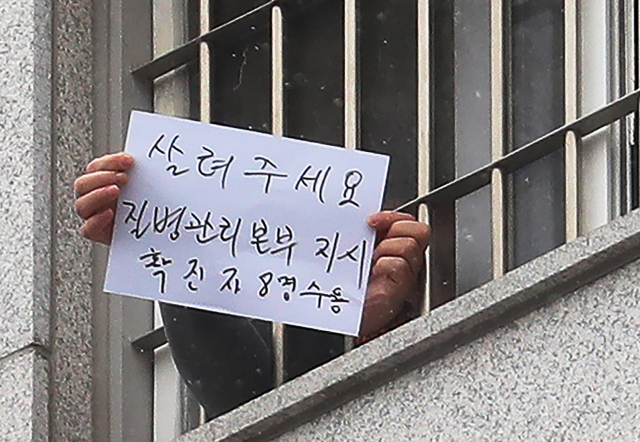 29일 오후 서울 송파구 동부구치소에서 한 수용자가 확진자 과밀 수용 등 불만사항을 직접 적어 취재진을 향해 들어보이고 있다. 어제 동부구치소에서 233명의 확진자가 추가돼 지금까지 이곳에서만 총 757명이 감염됐다. [연합]