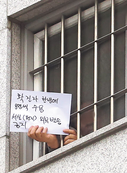 지난달 29일 오후 서울 송파구 동부구치소에서 한 수용자가 확진자 과밀수용과 서신 발송 금지 등 불만 사항을 직접 적어 취재진을 향해 들어 보이고 있다. [연합]