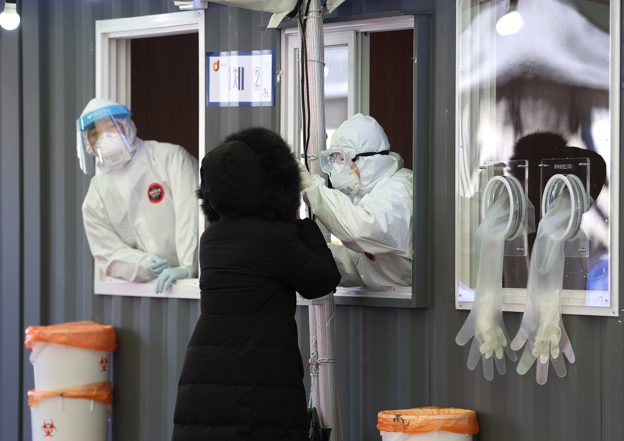 세밑 한파가 찾아온 30일 오전 서울역광장에 마련된 코로나19 임시선별진료소에서 의료진이 검체를 채취하고 있다. 연합뉴스