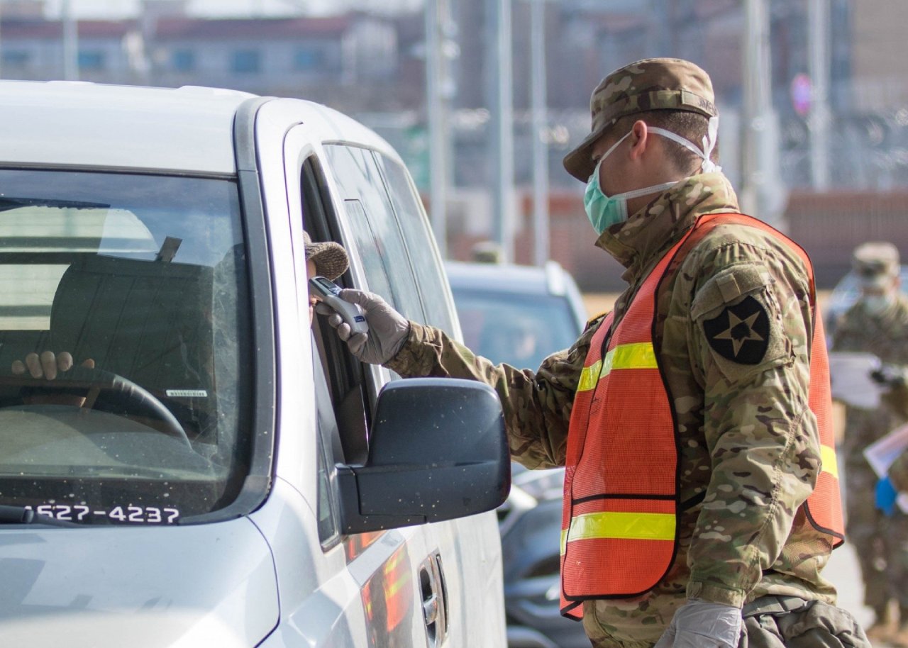 A military guard at US Army Garrison Humphreys in Pyeongtaek, 70 kilometers south of Seoul, checks the temperature of a driver to screen entrants to the compound for the novel coronavirus, on Feb. 28, 2020, in the photo provided by US Forces Korea. (USFK)