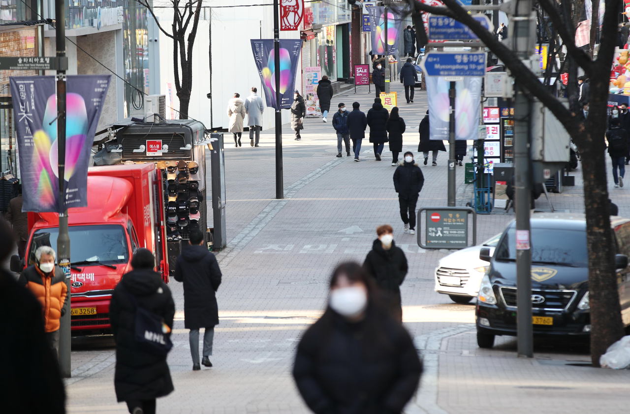 People wearing masks walk at Myeongdong shopping district in central Seoul on Thursday. (Yonhap)