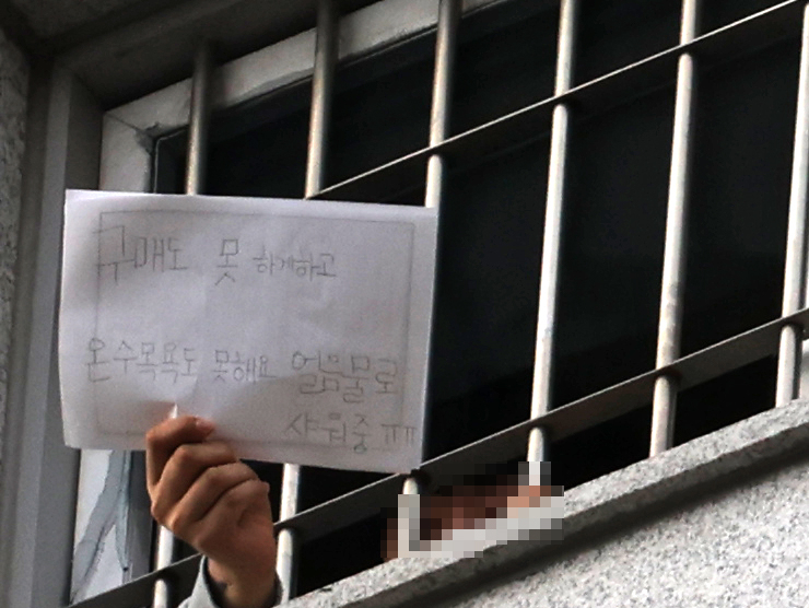3일 오후 코로나19 확진자가 다수 발생 중인 서울 송파구 동부구치소에서 한 수용자가 “구매도 못 하게 하고, 온수 목욕도 못해요”라고 적은 폭로성 메모를 취재진에게 보여주고 있다. [연합]